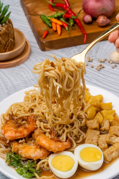 Mie rebus medan o zuppa di noodle Il piatto è composto da noodles all'uovo gialli che vengono utilizzati anche in Hokkien mee con un sugo speziato leggermente dolce simile al curry Il sugo è composto da gamberi o brodo tauchu