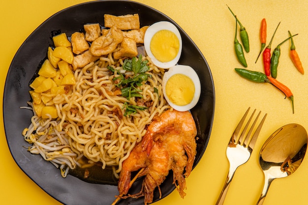 Mie rebus medan o zuppa di noodle Il piatto è composto da noodles all'uovo gialli che vengono utilizzati anche in Hokkien mee con un sugo speziato leggermente dolce simile al curry Il sugo è composto da gamberi o brodo tauchu