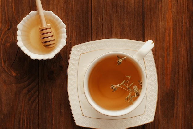 Miele di tiglio fresco liquido in un piatto con un cucchiaio di miele di legno e tè