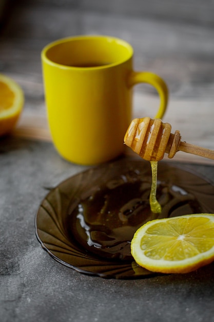 miele gocciolante su un piattino su grigio con tazza gialla