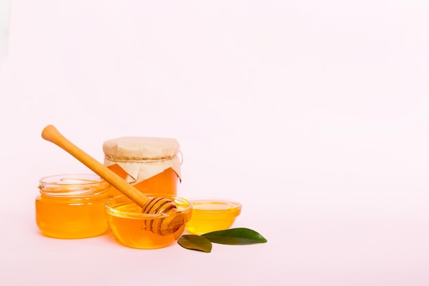 Miele in barattolo con foglie e mestolo di miele su sfondo colorato vista dall'alto con testo di copia