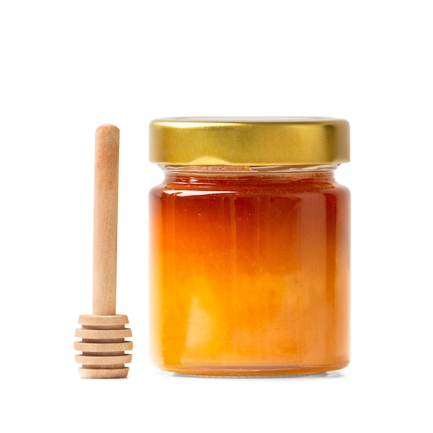 Miele in un barattolo con un mestolo di legno su uno sfondo bianco isolato