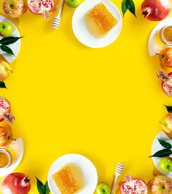 Miele, mela e melograno su sfondo giallo. Concetto Capodanno ebraico Felice vacanza Rosh Hashanah. Layout creativo di simboli tradizionali. Vista dall'alto. Copia spazio. Cornice per carte.