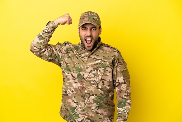 Militare isolato su sfondo giallo facendo un gesto forte