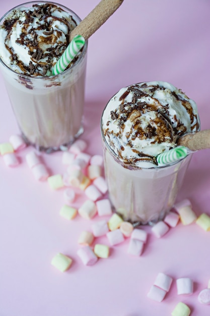 Milkshake al cioccolato con gelato e panna montata, marshmallow, biscotti, cialde, serviti in una tazza di vetro.