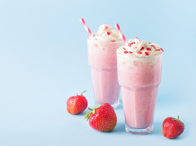 Milkshake alla fragola o frullato e bacche fresche crude sul blu