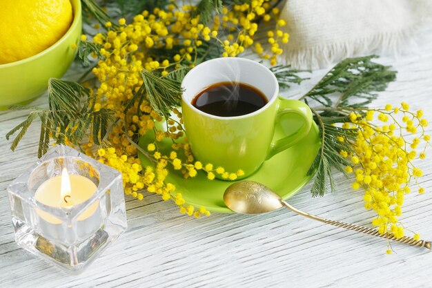 Mimosa, limone e caffè sul tavolo in legno chiaro