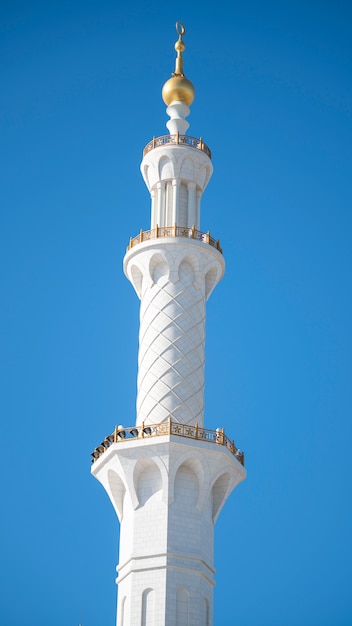 Minareto bianco della moschea nel fondo del cielo blu