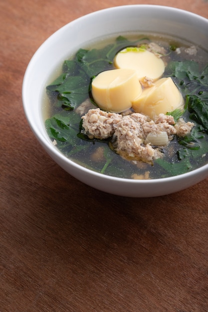 Minestra bollita del tofu e della carne di maiale tritata con la zucca in ciotola bianca sulla tavola di legno, alimento tailandese, alimento sano.