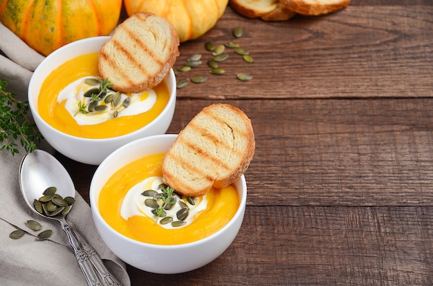 Minestra crema di zucca con crema e semi di zucca su di legno.