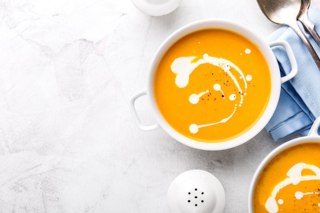 Minestra cremosa della zucca fresca saporita con crema su fondo di marmo grigio.