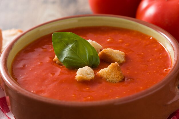 Minestra del pomodoro in ciotola marrone sulla tavola di legno