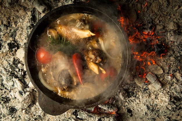 Minestra di carne con verdure preparata sui carboni ardenti. il piatto è cotto e affumicato alla brace