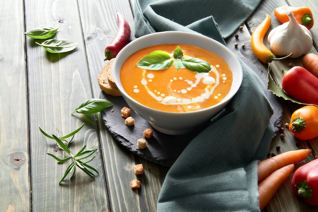 Minestra di carota piccante con peperoni al forno, peperoncino e aglio su legno