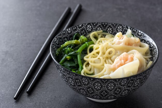 Minestra di Wonton in una ciotola sull'alimento cinese dell'ardesia