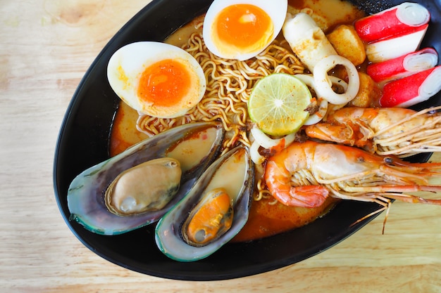 Minestra piccante del gamberetto delle tagliatelle in ciotola nera sulla tavola di legno, kung di Tom Yum