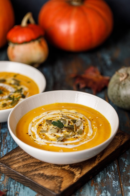 Minestra vegetariana di crema di zucca autunnale con semi in ciotole bianche. Zuppa di zucca