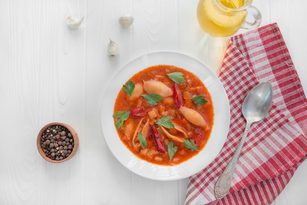 Minestrone con pasta ed erbe aromatiche. Cucina italiana. Piatto vegetariano. Tavolo da pranzo. Fondo di legno bianco. Copia spazio.