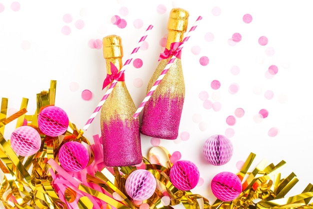 Mini bottiglie di champagne rosa e oro con coriandoli e orpelli. Disposizione piatta. Tema di celebrazione del nuovo anno o concetto di matrimonio