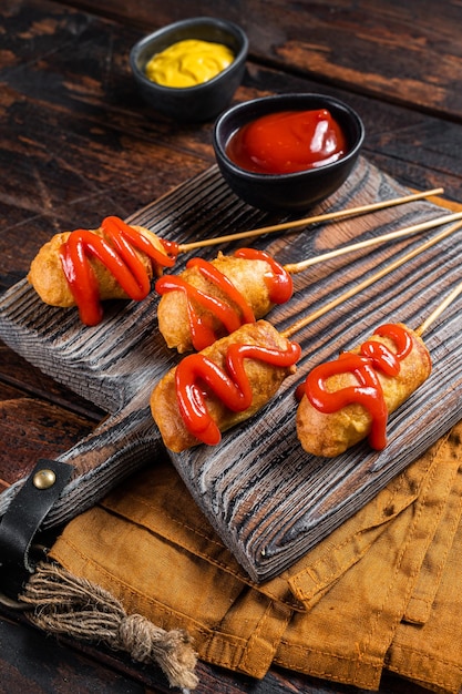 Mini cani di mais fritti con senape e ketchup su tavola di legno Sfondo in legno Vista dall'alto