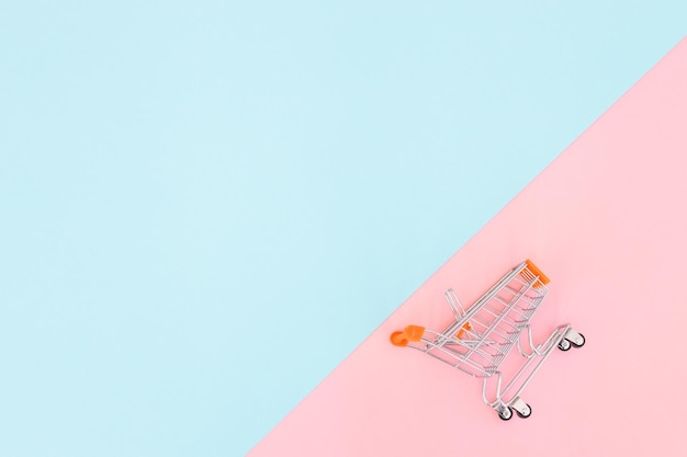 Mini carrello della spesa di concetto di consumatore per lo shopping su uno sfondo colorato minimalismo vista dall'alto