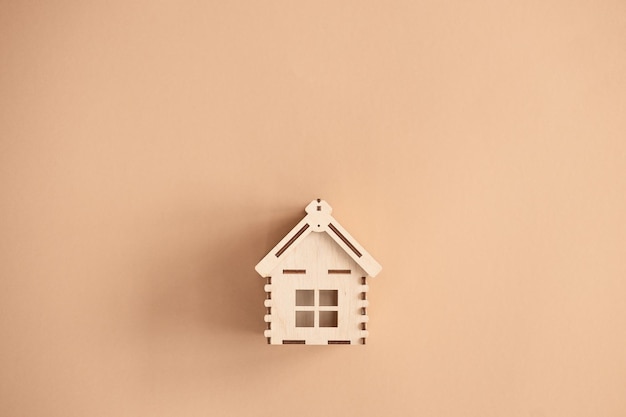 Mini casa in legno su sfondo beige Concetto di residenza e prestito casa