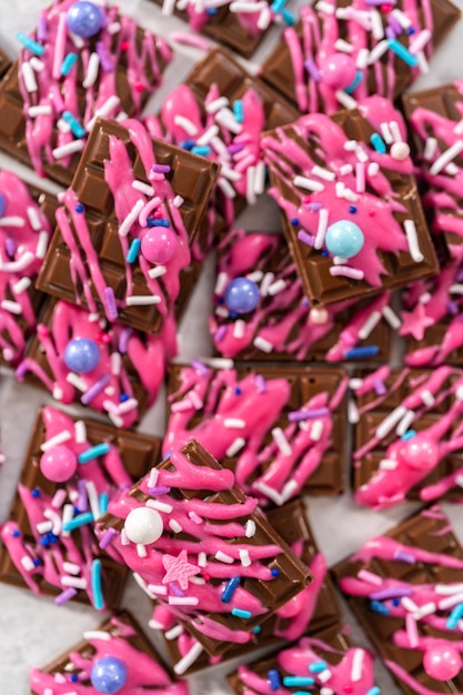 Mini cioccolatini fondenti gourmet con cioccolato rosa spruzzato e granelli fantasia sulla parte superiore.