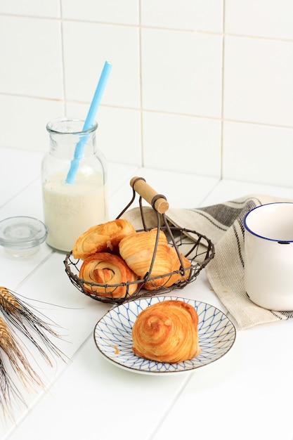 Mini croissant al latte, pasta sfoglia al burro dalla francese. Servito su piatto e cesto in filo intrecciato su cucina bianca. Copia spazio per il testo.