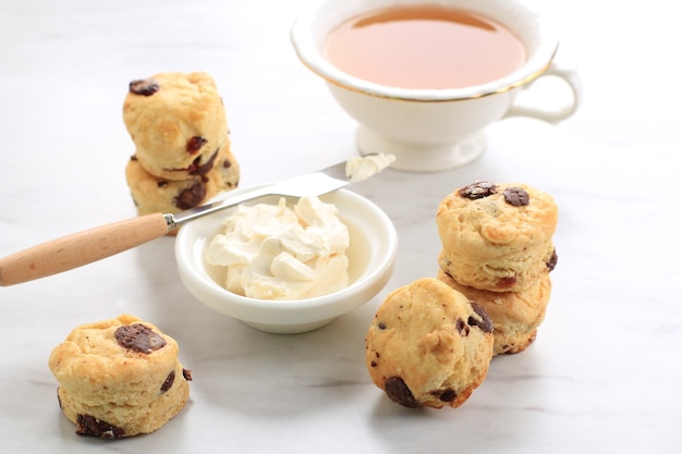 Mini focaccine rotonde con panna rappresa e una tazza di tè, fondo in marmo bianco