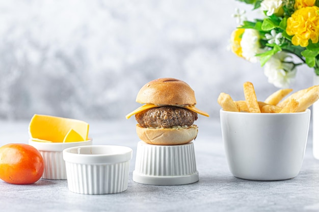 Mini hamburger di manzo con patatine fritte e formaggio sulla vista frontale del tavolo