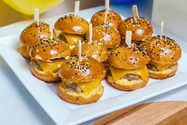 Mini hamburger di pollo sul piatto bianco La cuoca tiene un piatto tra le braccia Composizione diagonale