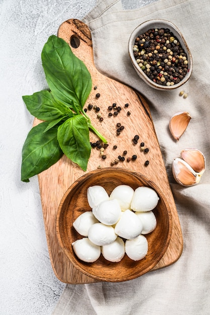 Mini mozzarella in una ciotola di legno con foglie di basilico