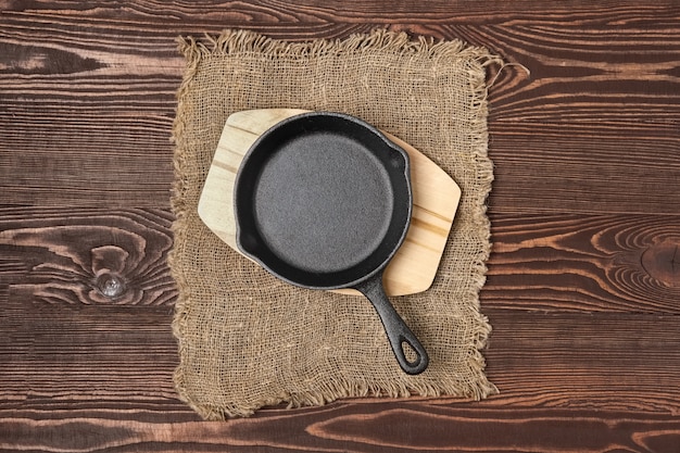 Mini padelle vuote della ghisa sulla tavola di legno, vista da sopra