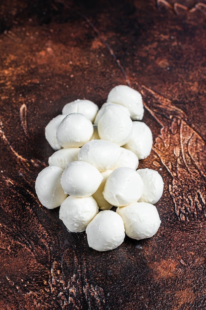 Mini palline di mozzarella di bufala sul tavolo della cucina. Sfondo scuro. Vista dall'alto.