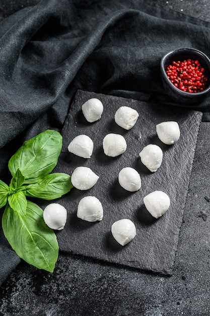 Mini palline di mozzarella, ingredienti per insalata Caprese. sfondo nero. Vista dall'alto