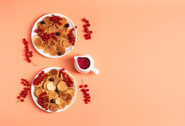 Mini pancake in ciotole con ribes su una superficie di pesca