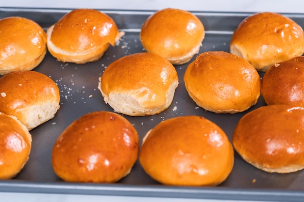 Mini panini per hamburger con brioche su una teglia.