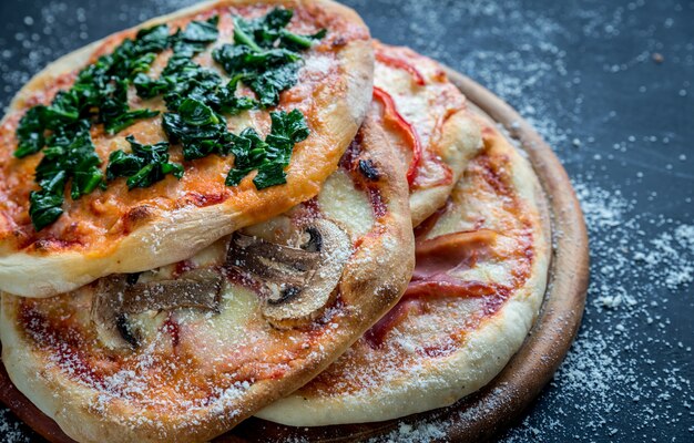 Mini pizze con vari condimenti sulla tavola di legno