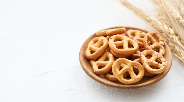 mini pretzel salato in un piatto di legno su sfondo bianco da tavola.