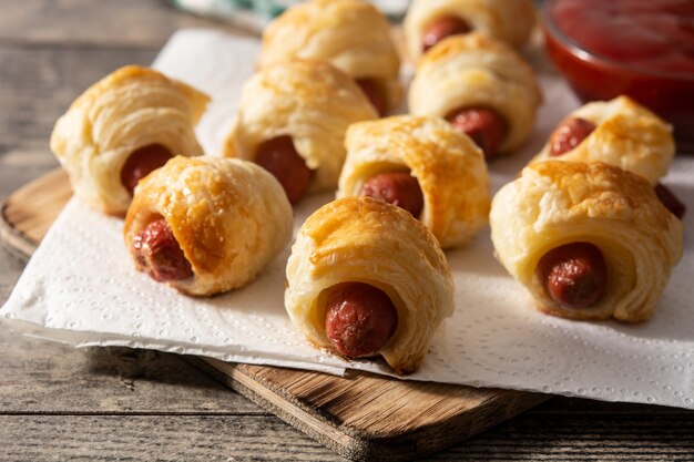 Mini salsicce avvolte in pasta sfoglia con salsa ketchup sul tavolo di legno