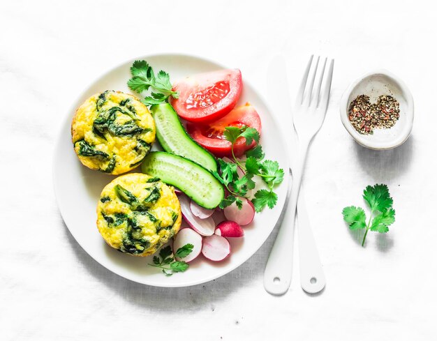 Mini spinaci cheddar frittata e insalata di verdure su sfondo chiaro vista dall'alto