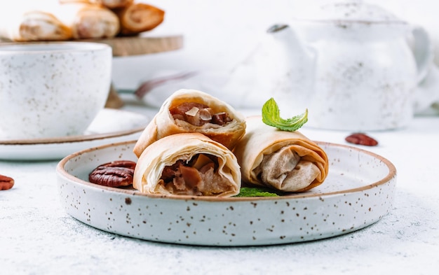 Mini strudel di mele fatto in casa con noci pecan e menta su sfondo bianco Pasticceria viennese Messa a fuoco selettiva