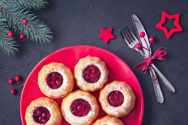 Mini torte ad anello con marmellata di mirtilli rossi sul buio con ramoscelli di abete e bacche