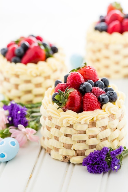 Mini torte del cestino di Pasqua con frutta fresca glassata sulla parte superiore.