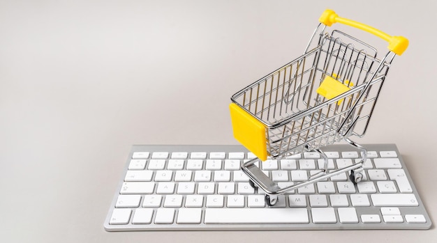miniature shopping cart on a keyboard on a gray background with copyspace