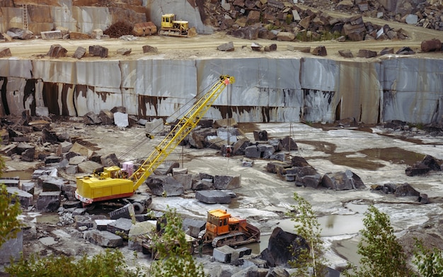 Miniera di pietra di granito con escavatori di attrezzature pesanti che caricano rocce grezze