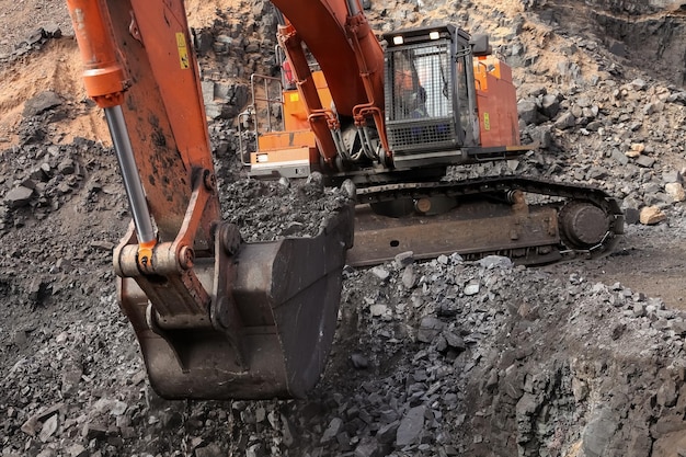 Miniere di manganese a cielo aperto - Escavatore che estrae roccia ricca di minerali e la carica su autocarri con cassone ribaltabile per la lavorazione