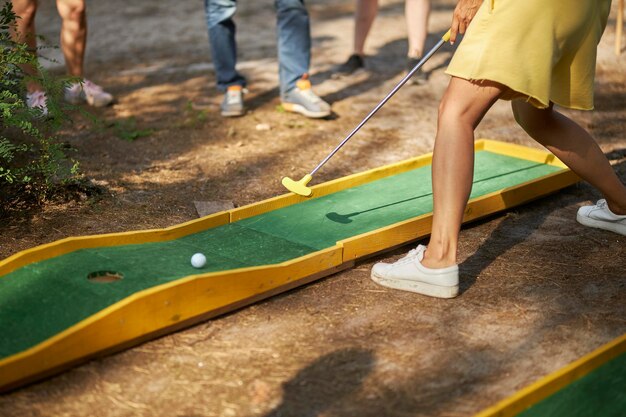 minigolf in natura giocatore di minigolf con scarpe da ginnastica bianche che mette la pallina da golf nella buca