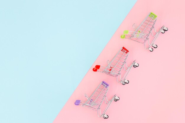 Minimalismo del concetto di consumatore Mini carrello della spesa per lo shopping su sfondo colorato vista dall'alto