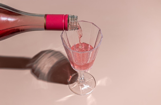 Minimo sfondo rosa pastello creativo rosa champagne che viene versato in un bicchiere di vino